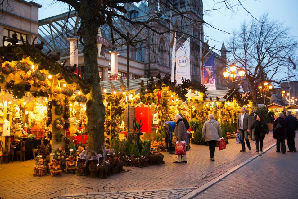 People and warmly lit stalls at Chester Christmas Market outside the Town Hall